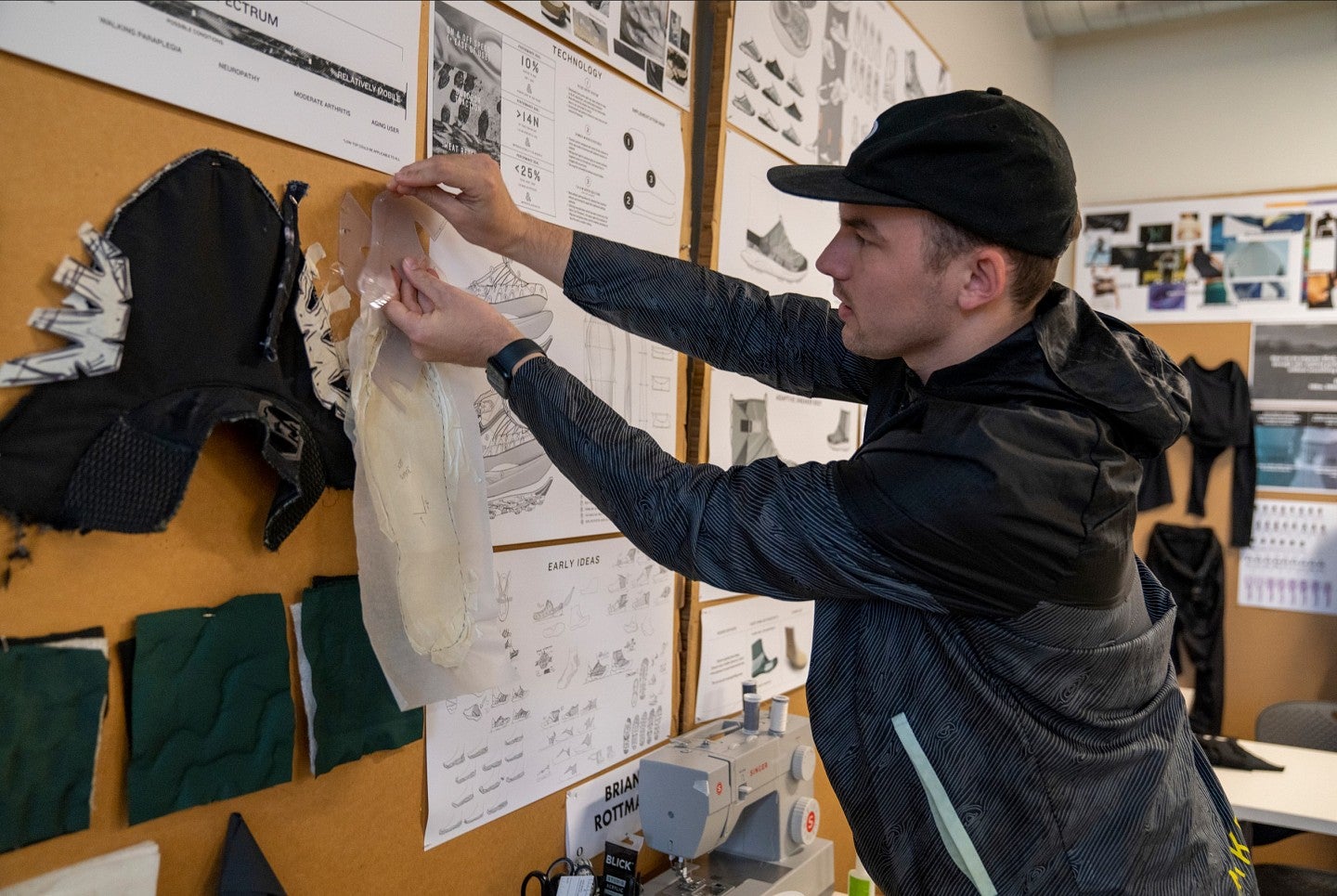 A student pins a design to a wall