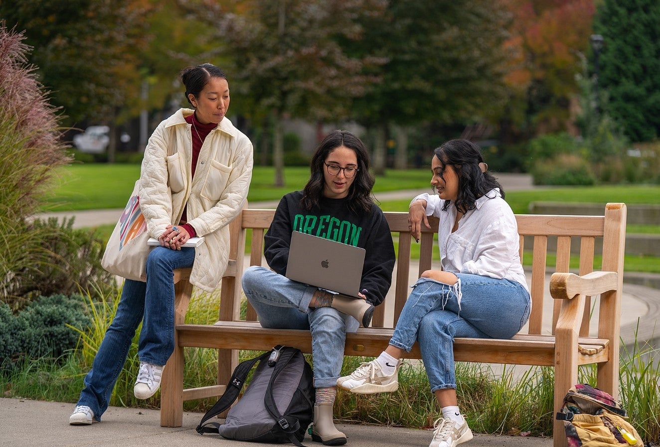 Three UO students work on a laptop