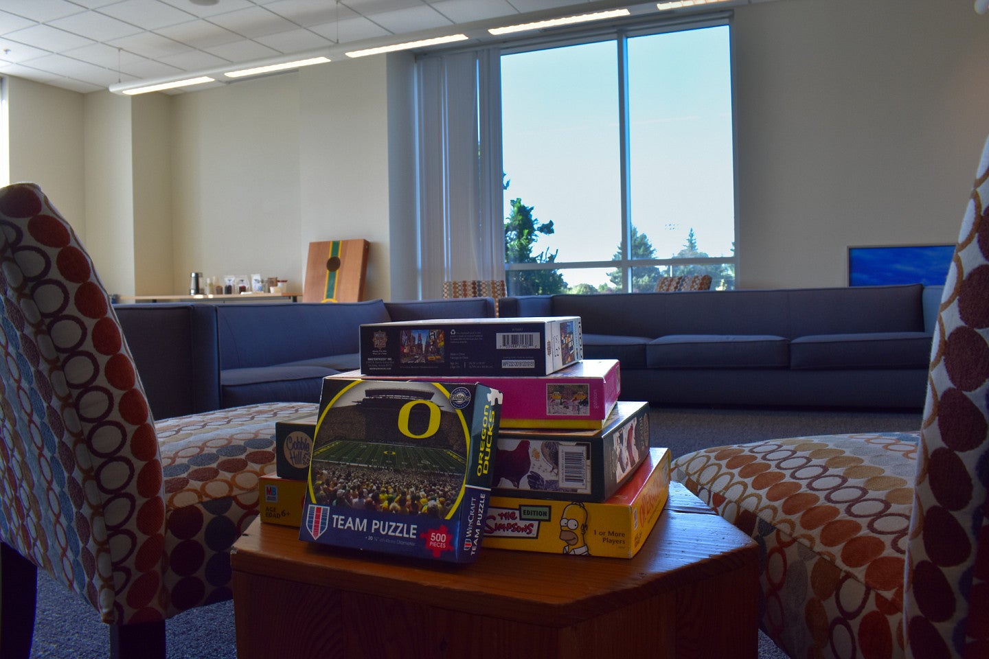Board games and a UO Puzzle stacked on a table in The Duck Den