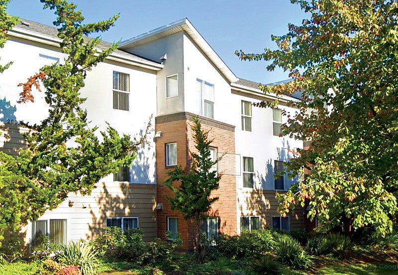 Photo of outside of Holman Apartments in Portland, OR. White and orange brick exterior.