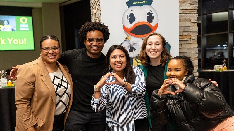Student Life team poses in front of The Duck. Two team members hold up their hands in an O-shape