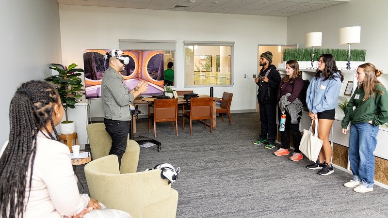 students stand in The Duck Nest. A man wears a VR headset