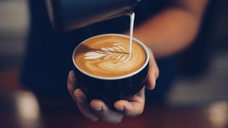 Barista making leaf design on the top of coffee with foam. 