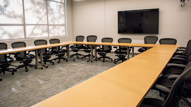 The classroom is set in a U-shape. There is a monitor screen on the back wall and a large window.