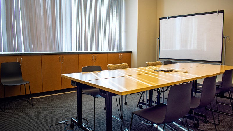 Small conference room with moveable white board and a large window.