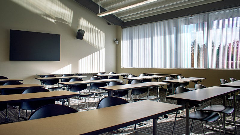 The back wall of the classroom has a screen. The large window overlooks the campus green. 
