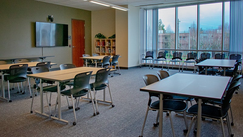 Classroom 203 is set with small clusters of tables for collaboration.