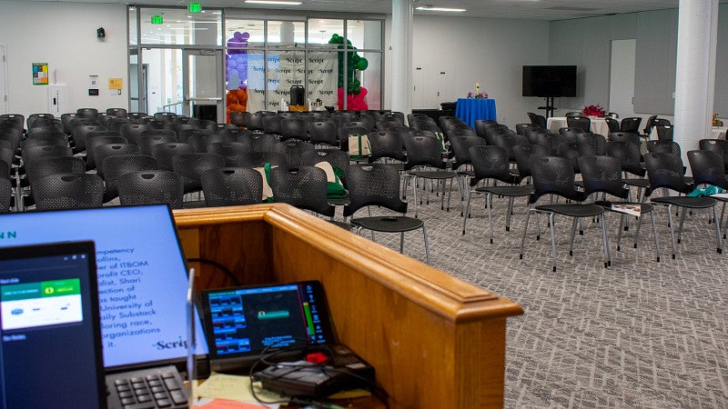 The room set with rows of chair. It has a podium and technology to control multiple screens in the room. 