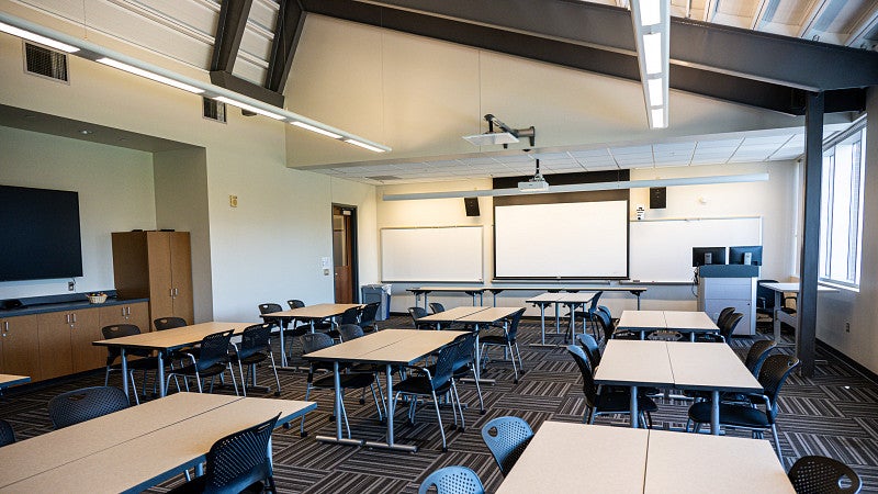 The classroom has a tall ceiling and built-in counter. 