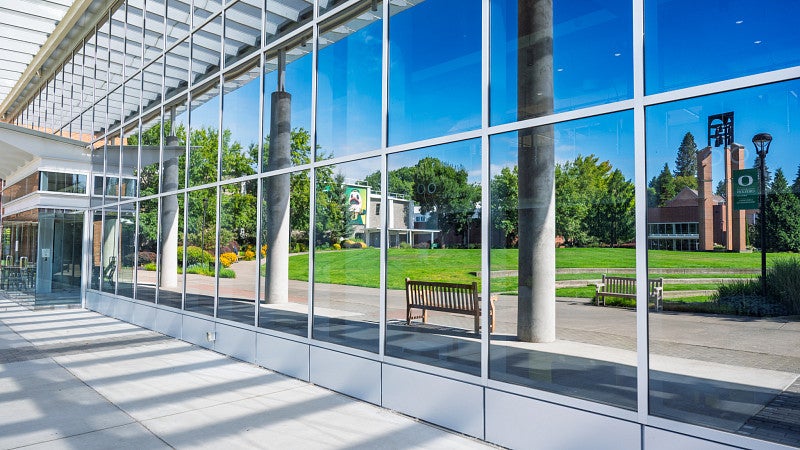 The bell tower, gymnasium and campus green are reflected in the windows of the Library & Learning Center. 