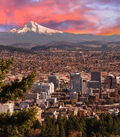 A landscape shot of Portland's cityscape at sunset with Mount Hood in the background.