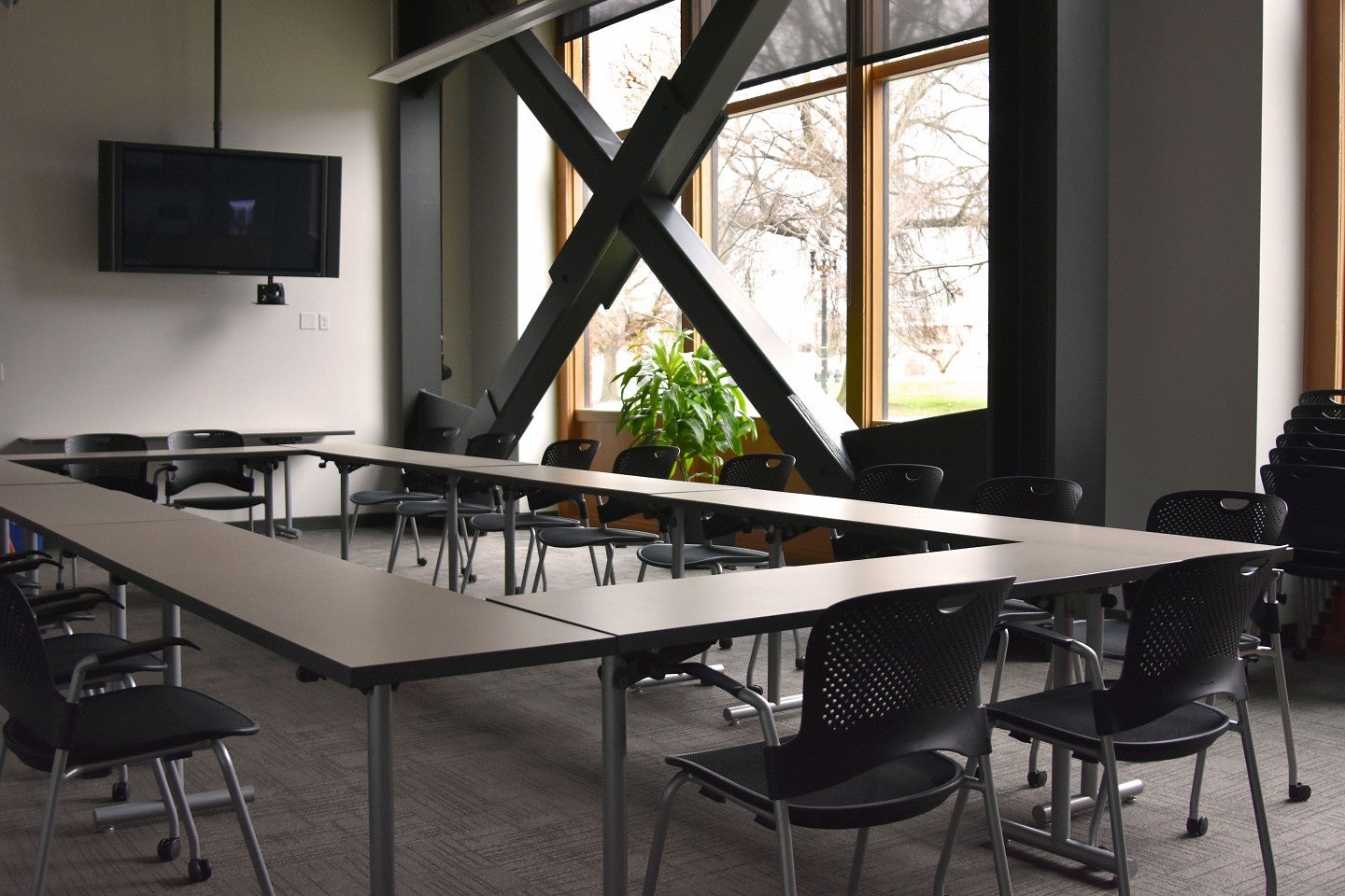 Classroom 150 with tables forming a rectangular shape and a screen. 
