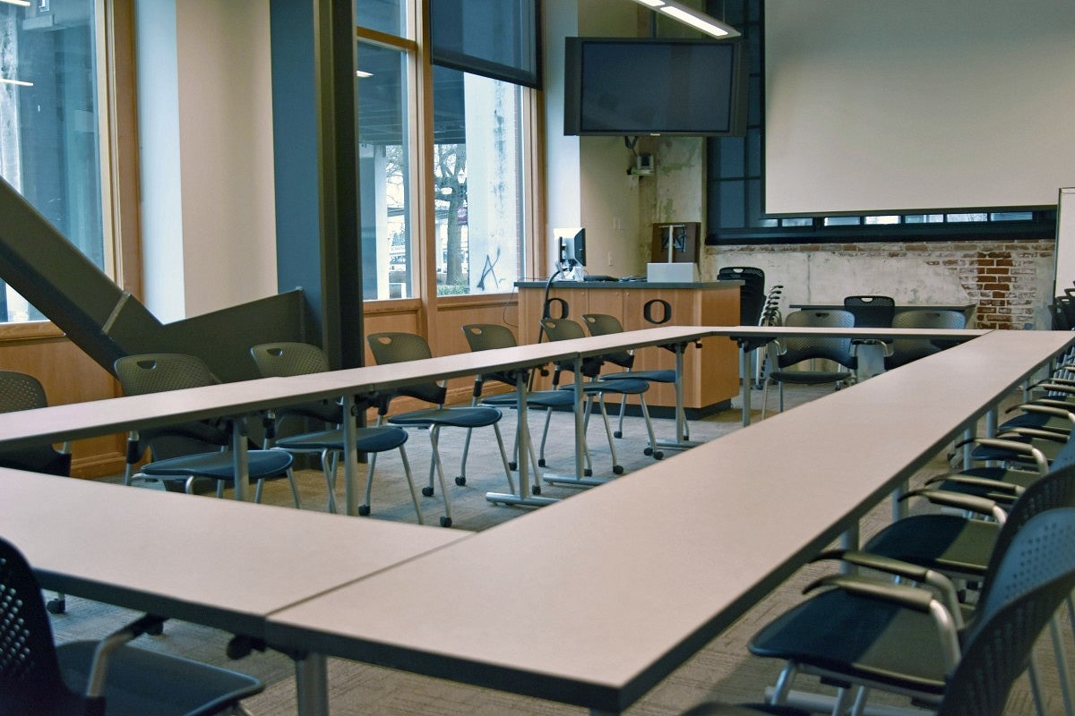 Classroom 150 with tables forming a rectangular shape and a screen.