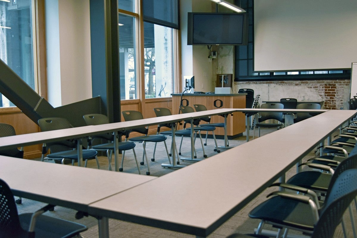 Classroom 150 Classroom 150 with tables forming a rectangular shape and a screen.