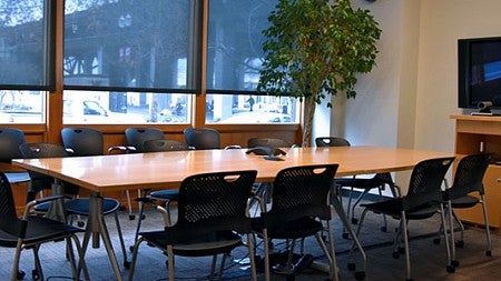 A conference room with a long table and chairs and a screen. 
