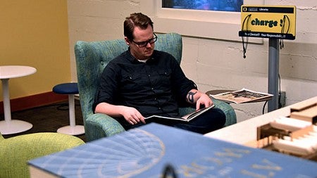 A library staff member reads in a chair in the library.