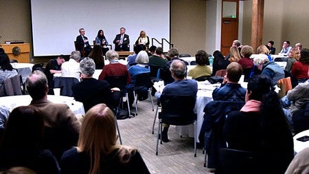 Speakers present to an audience in the main event space.