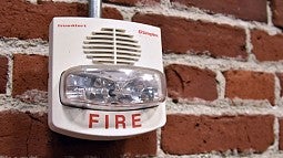 A fire alarm against a brick wall. 