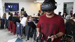 Student wearing a virtual reality headset with a class behind him