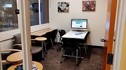 The library's study room includes a desk, a computer on a standing desk and chairs. 