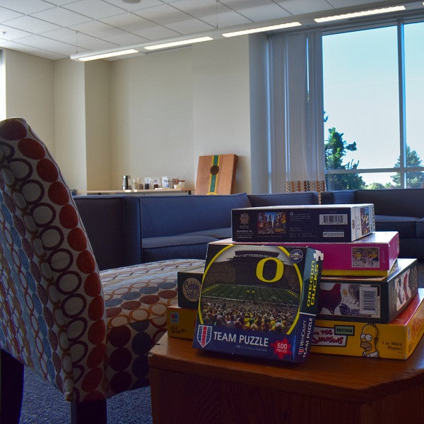 Board games and a UO Puzzle stacked on a table in The Duck Den
